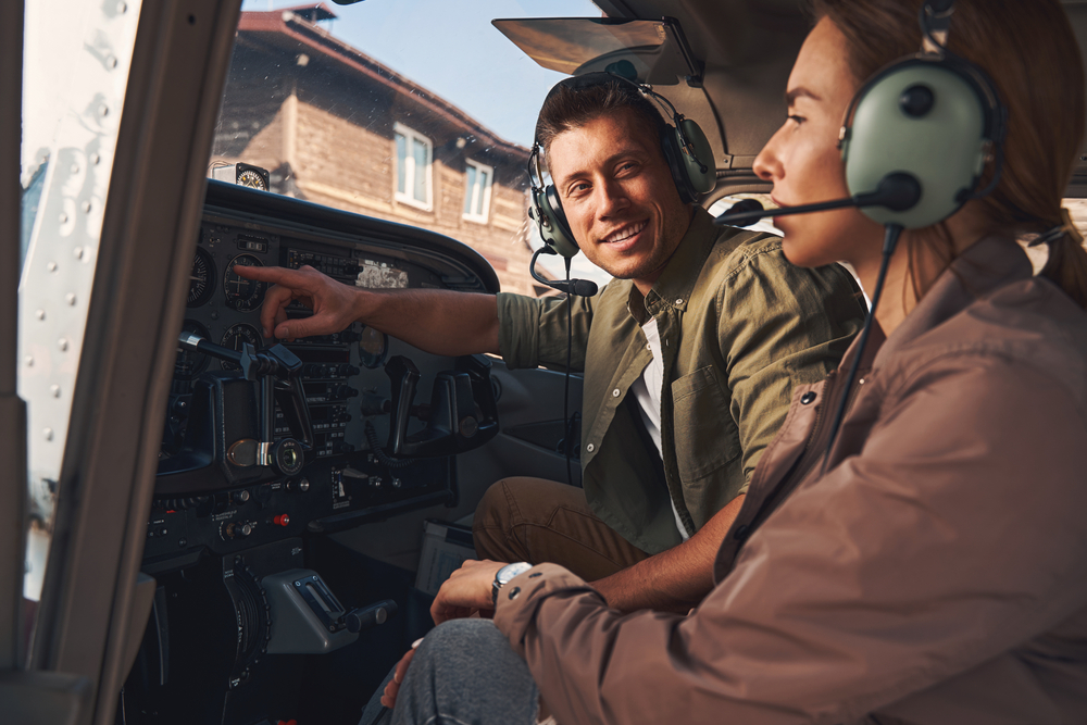 Cheerful,young,man,giving,flight,lesson,to,woman